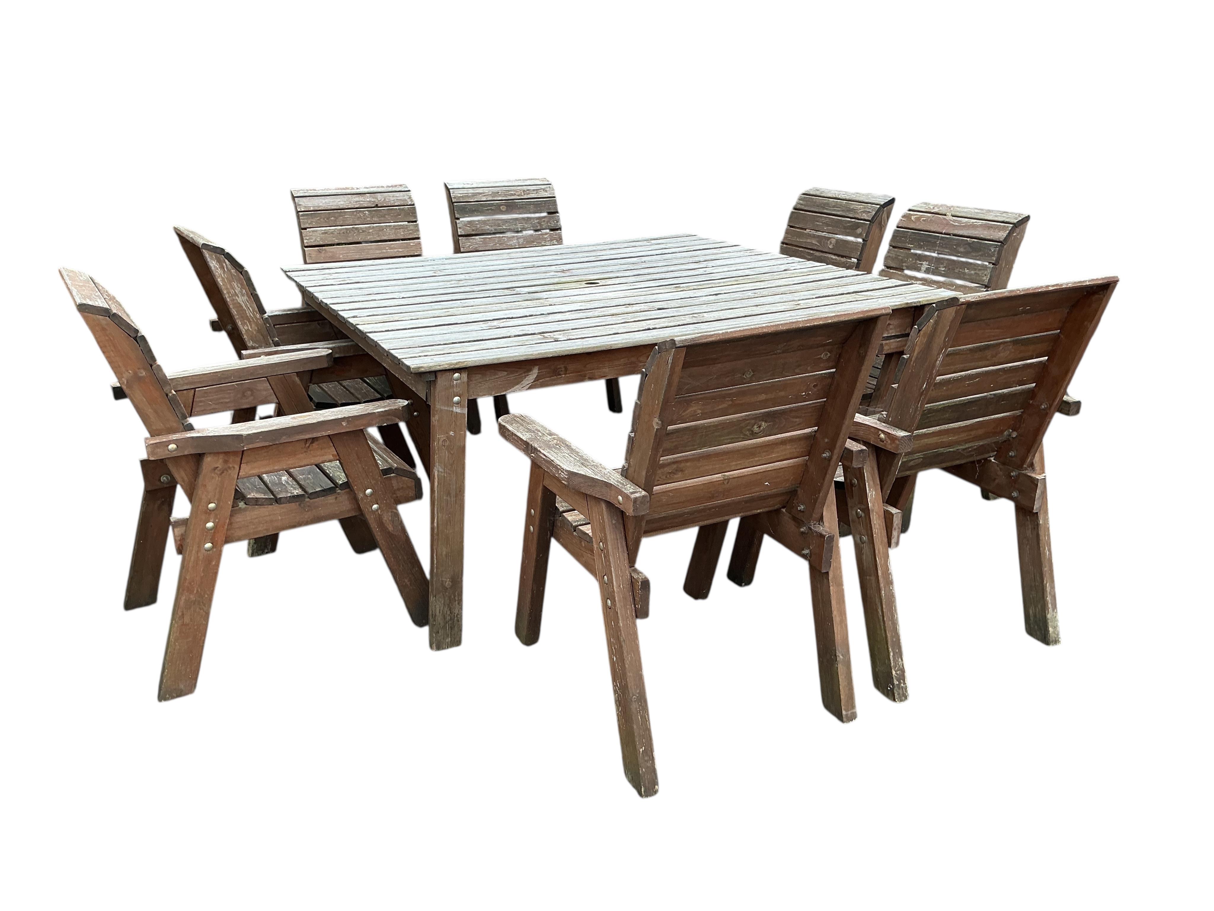A large square weathered teak garden table, 161cm, height 80cm and set of eight matching slatted wood armchairs